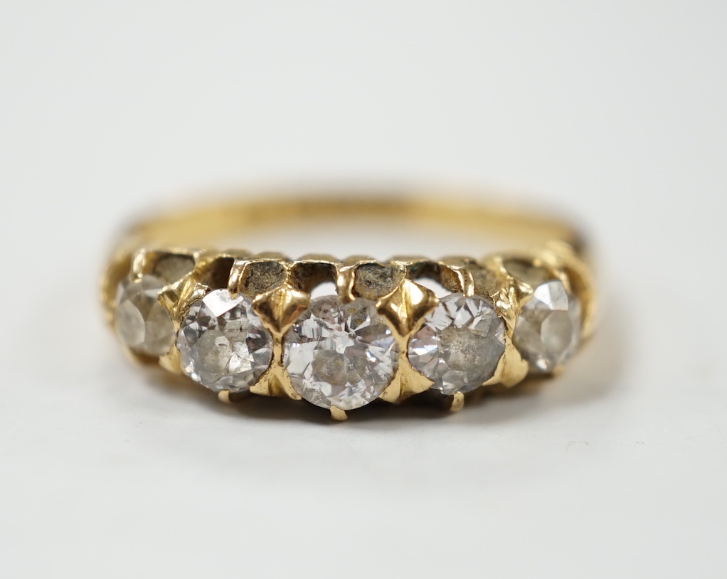 A late Victorian 18ct gold and graduated five stone diamond set half hoop ring, size L/M, gross weight 3.6 grams.